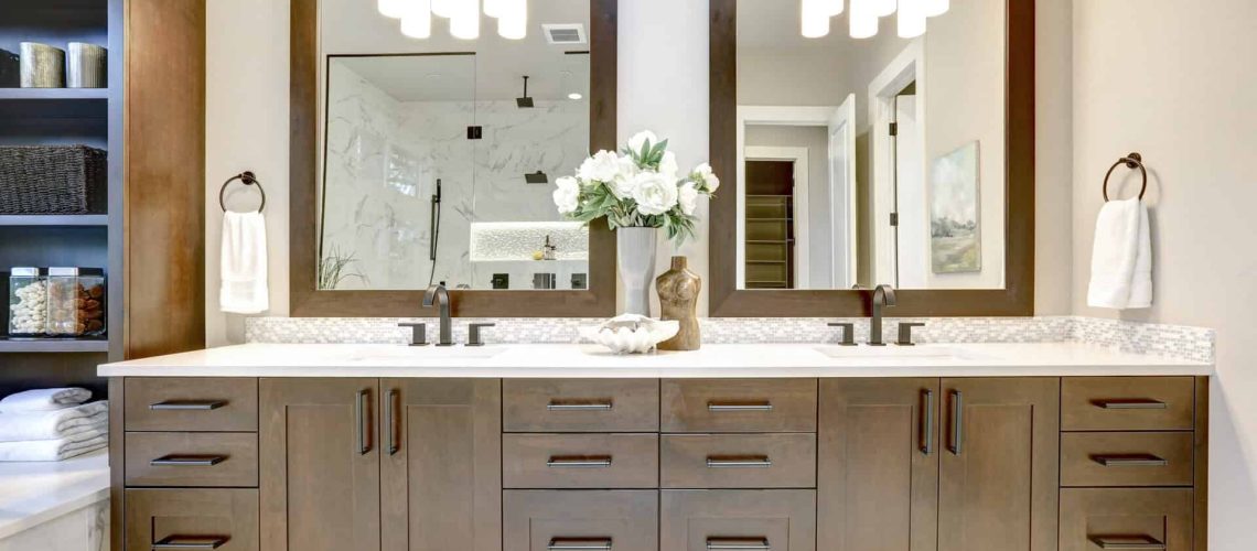 Master bathroom interior in luxury modern home with dark hardwood cabinets, white tub and glass door shower