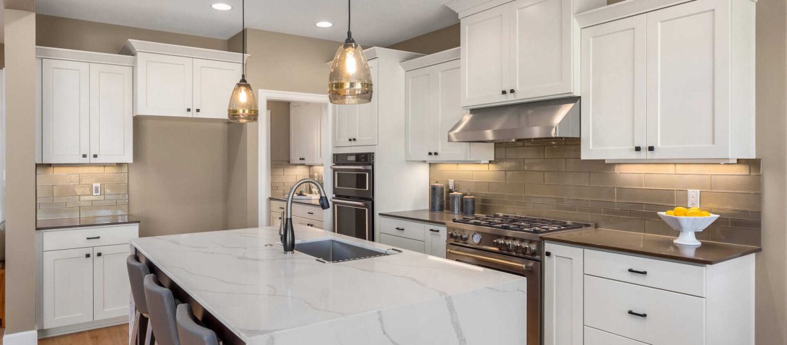 Kitchen in new luxury home with waterfall isalnd, stainless steel appliances, pendant lights, and hardwood floors