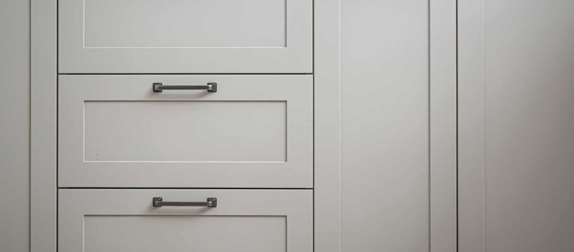 White kitchen cabinets with metal pulls or knobs on the doors close up.