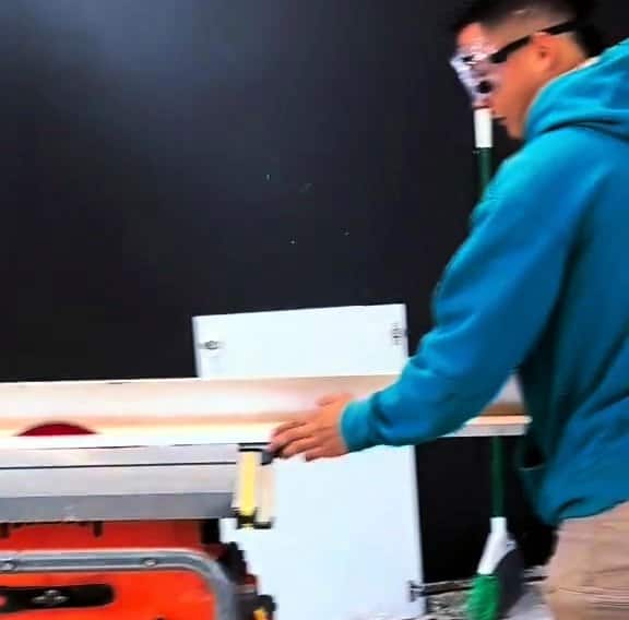 LuxeCraft installer in safety glasses cutting a cabinet panel on a table saw