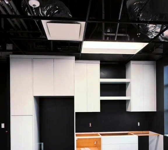 Wall of custom white flat-panel built-in cabinets installed by LuxeCraft in a commercial space