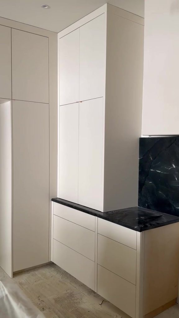 Custom white cabinets with black stone countertop being installed by LuxeCraft in a new home