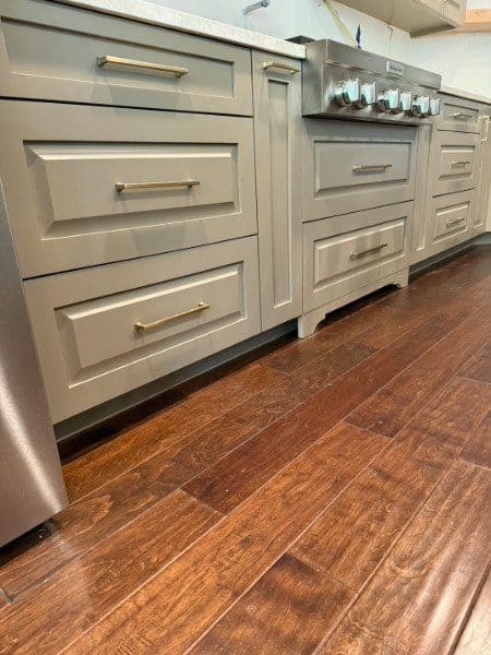 Custom recessed-panel kitchen drawers with brass bar pulls by LuxeCraft