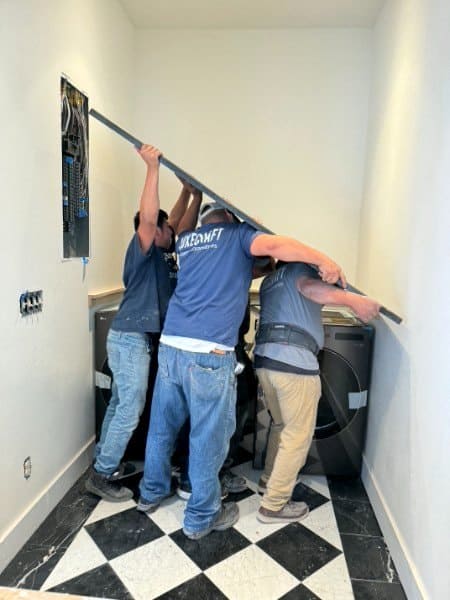 LuxeCraft installation crew in branded shirts setting a countertop in a laundry room in San Antonio