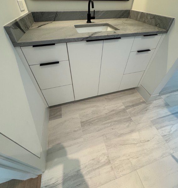 Modern white flat-panel bathroom vanity with gray stone countertop and black pulls by LuxeCraft