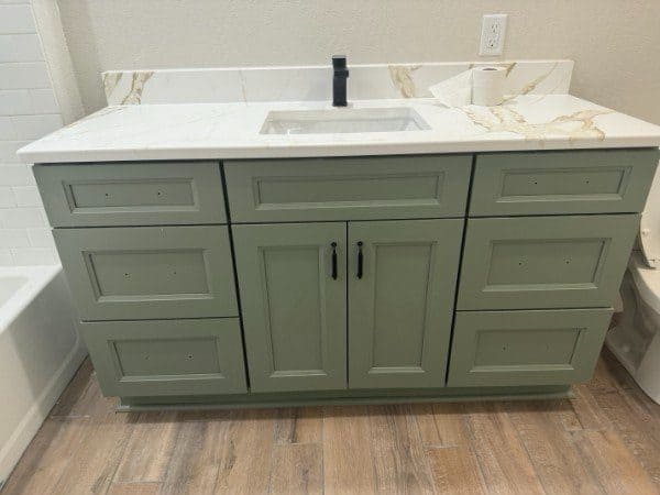 Sage green bathroom vanity with gold-veined quartz countertop by LuxeCraft