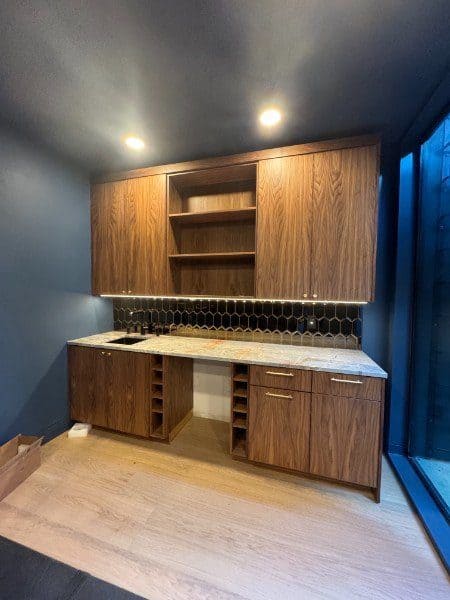 Walnut wet bar with custom cabinets, open shelving, wine storage and hex tile backsplash by LuxeCraft